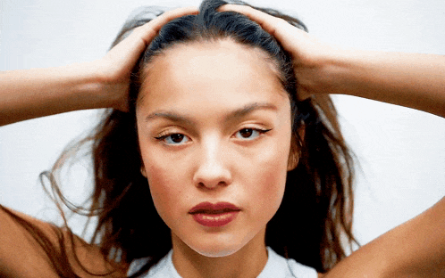 a close up of a woman 's face with her hands on her hair