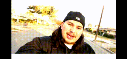 a man wearing a black hat with the letter b on it takes a selfie