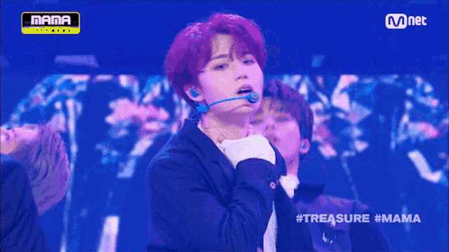 a boy with red hair is on a stage with a mnet logo above him