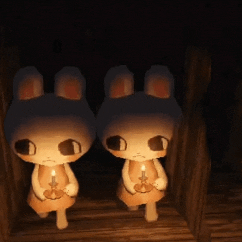two stuffed bunny rabbits holding candles in their hands