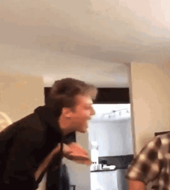 a man is making a funny face while standing in a room .