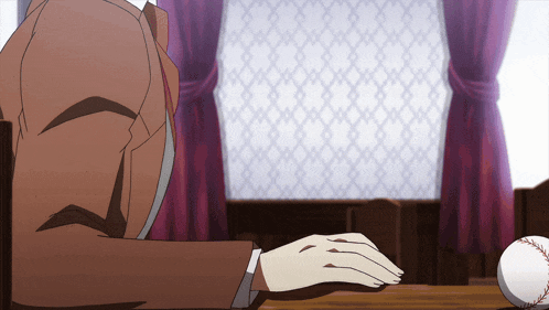 a man in a suit is sitting at a table with a baseball in front of him