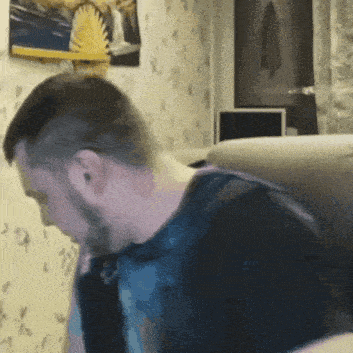 a man with a beard is sitting on a couch and looking down