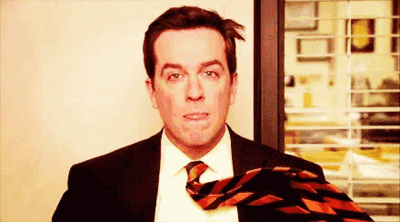 a man in a suit and tie is adjusting his tie and making a funny face .