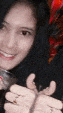 a blurry picture of a woman holding a glass and giving a thumbs up