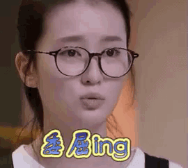 a woman wearing glasses is making a funny face and the word bing is on the bottom of her face .