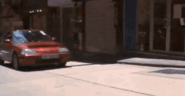 a red honda civic is parked on the side of the road .
