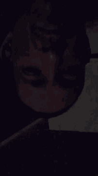 a close up of a man 's face in the dark with his eyes closed