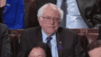 a man in a suit and tie is sitting in a theatre applauding