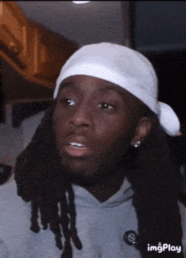 a man with dreadlocks is wearing a white bandana
