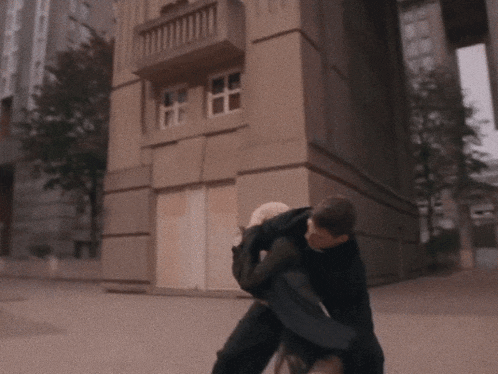 a man is carrying a woman on his back in front of a building
