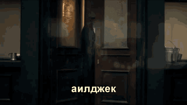 a man in a suit stands in front of a door that says " auldjek " on it