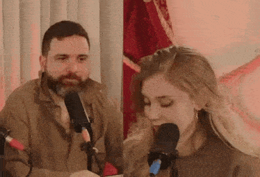 a man and a woman are singing into microphones while sitting in front of a microphone .