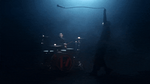 a man is holding a microphone in front of a drum set that has the letter h on it