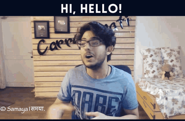 a man wearing glasses and a dare t-shirt is saying hi hello