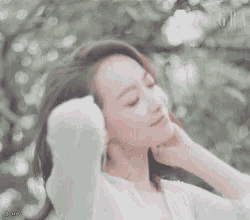 a woman wearing a white sweater holds her hand to her chin