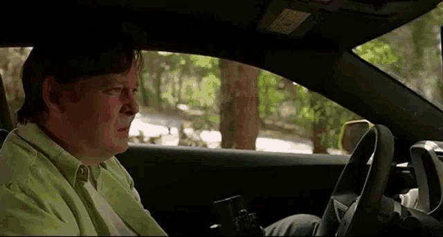 a man is sitting in the driver 's seat of a car holding a gun .