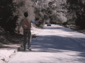 a man is walking down the side of a road while a car is driving down it .