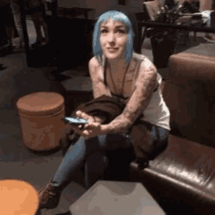 a woman with blue hair is sitting on a couch
