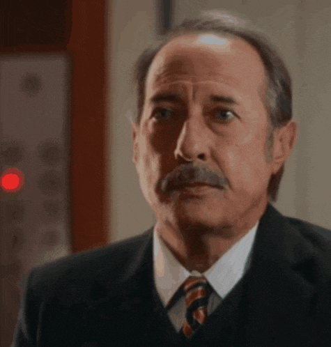 a man in a suit and tie looks at the camera