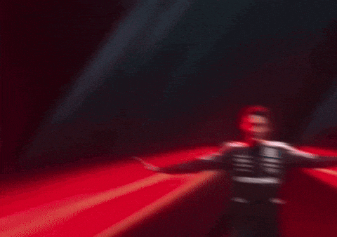 a man in a skeleton costume is dancing in a dark room with red lights behind him .