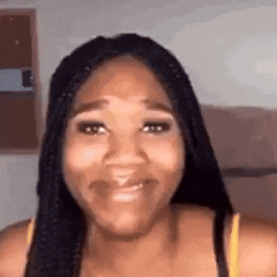 a woman with braids is smiling and looking at the camera while wearing a yellow tank top .