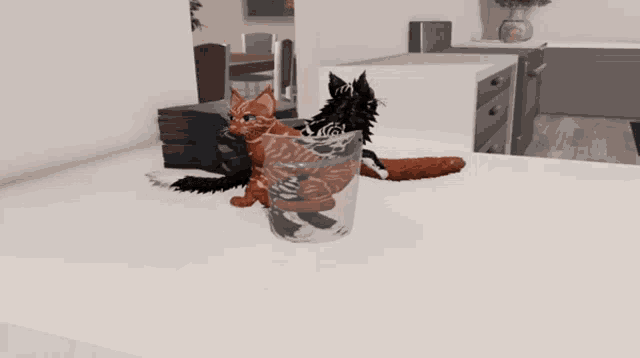 two cats are sitting in a glass on a counter