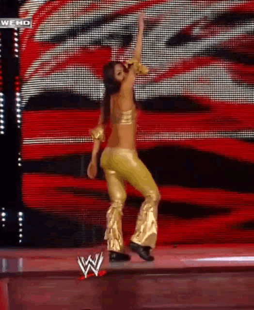 a woman in gold pants is dancing on a stage in front of a large screen that says we hd