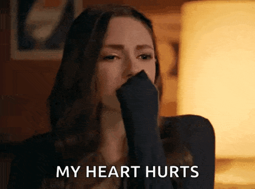 a woman is crying and saying `` my heart hurts '' while covering her mouth with her hand .