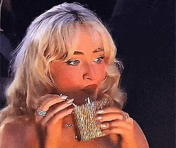 a blonde woman is smoking a cigarette while holding a purse in her hands .