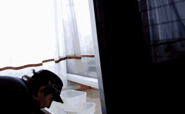 a man wearing a hat that says ' samurai ' on it is looking out a window