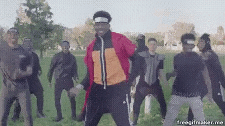 a man in a red jacket is dancing in a field with a group of people .