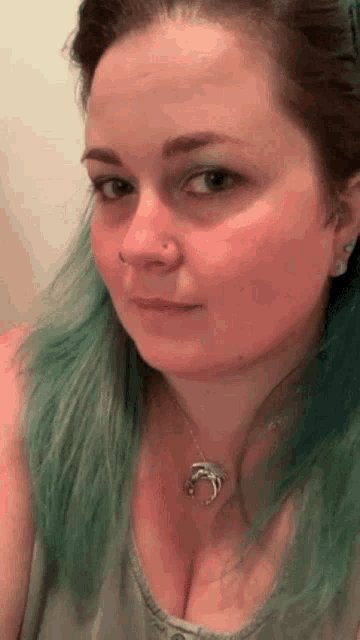 a woman with green hair is wearing a necklace with a dolphin pendant