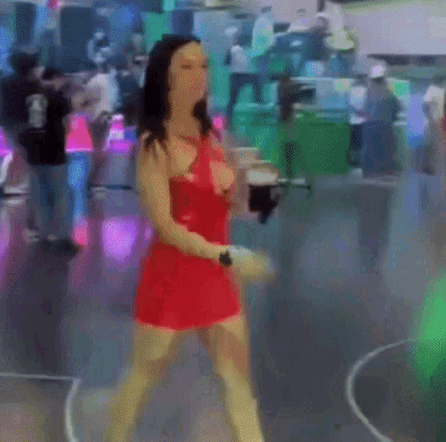 a woman in a red dress is dancing on a dance floor in a club .