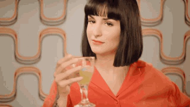 a woman in a red shirt is holding a glass