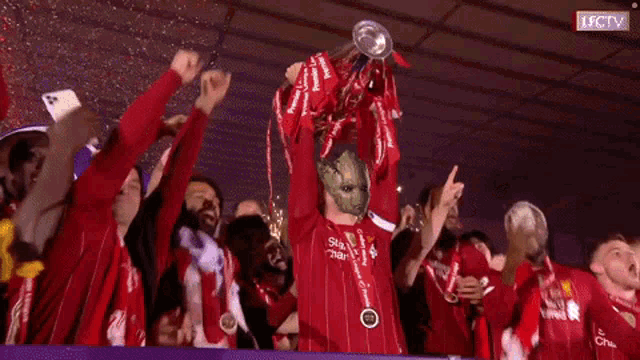 a group of soccer players holding up a trophy that says ' lfctv ' on it
