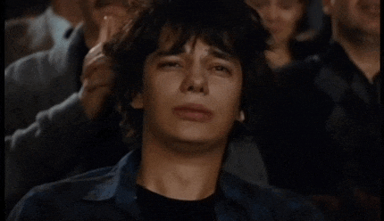 a man sitting in a crowd with his eyes closed and his hand on his head