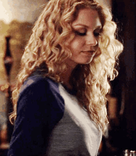 a woman with curly blonde hair wearing a blue shirt