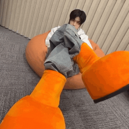 a person is sitting on a bean bag chair with their feet on a stuffed orange duck .
