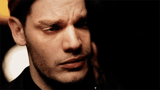 a close up of a man 's face with a woman 's hand on his ear .