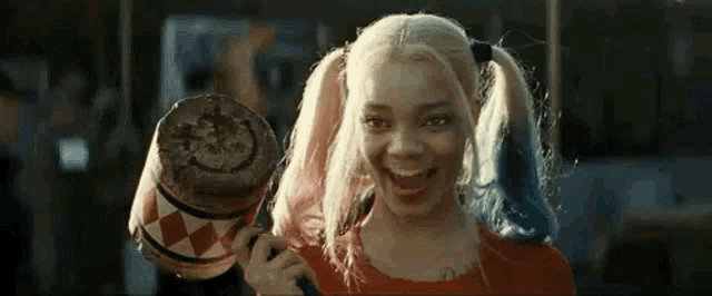 a woman in a harley quinn costume is holding a mallet .