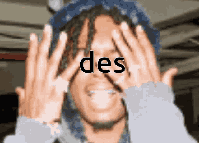 a person covering their face with their hands with the word des written on it