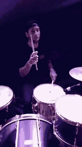 a man playing drums with a shirt that says ' uc ' on the front