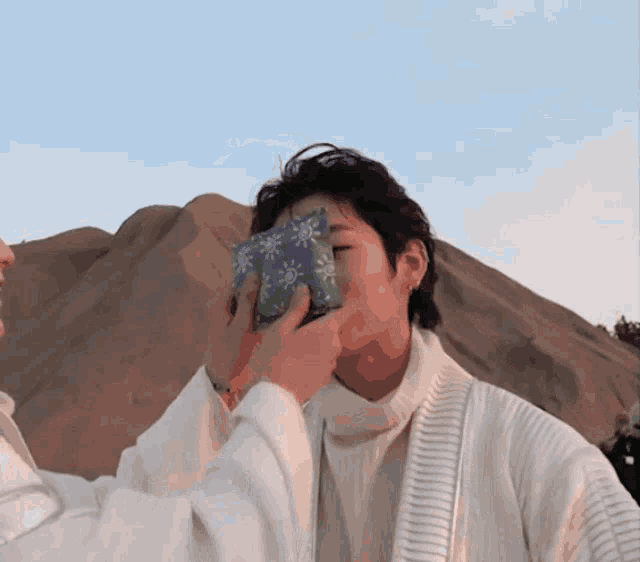 a person covering another person 's face with a piece of cloth