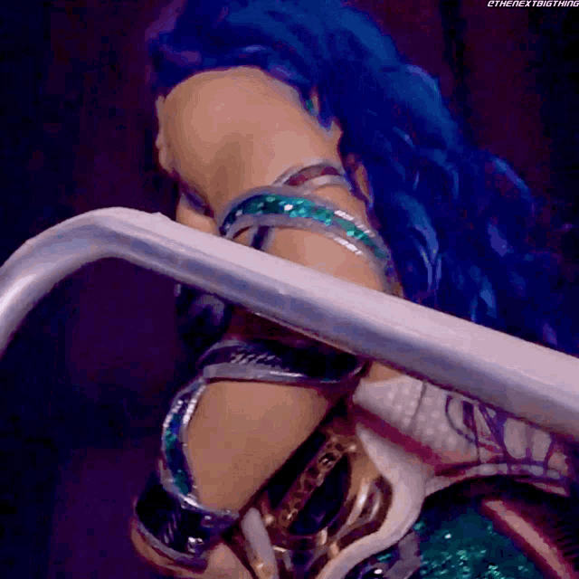 a woman with blue hair is standing next to a railing with the hashtag #thenextbig thing