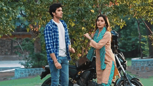 a man and a woman stand next to a motorcycle