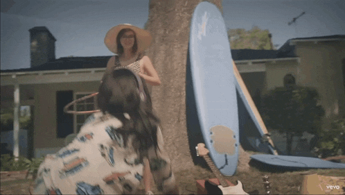 a woman wearing a hula hoop stands next to a blue surfboard that says ' hawaii ' on it