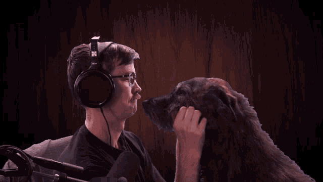 a man wearing headphones and a microphone holds a dog