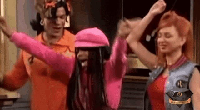 a group of people are dancing with their arms in the air in a room .
