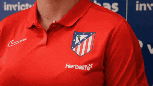 a woman is wearing a red shirt with a herbalife logo on it